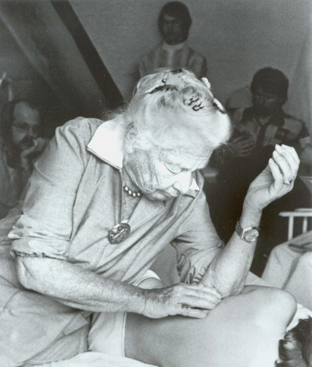 Historic photograph of Dr. Ida Rolf working hands-on with a client on a table